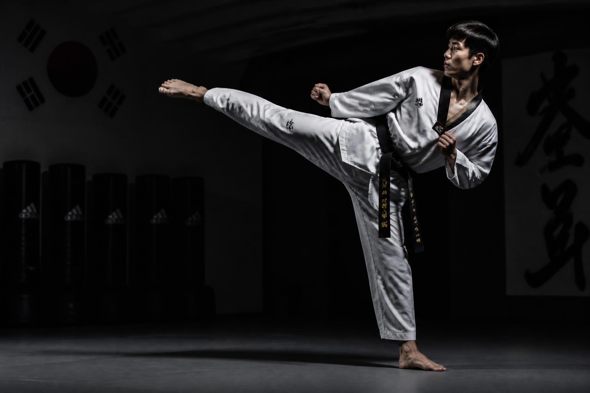 Black belt performing a side kick in the dojang